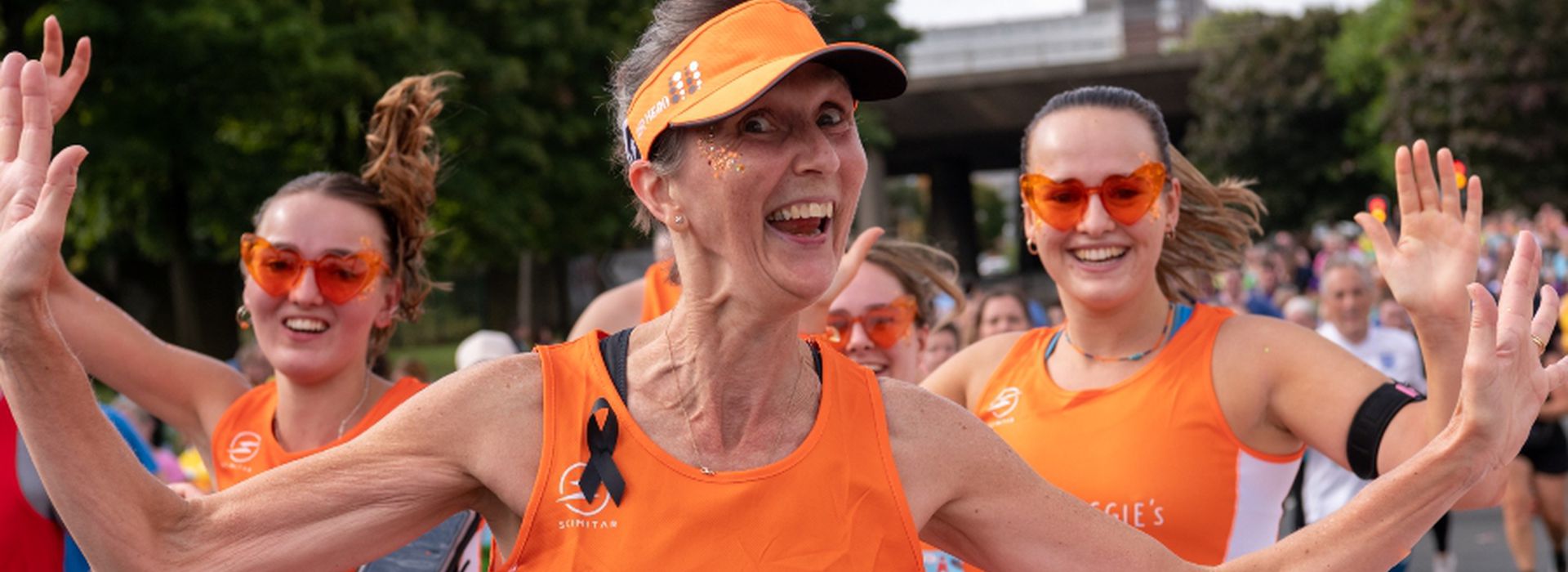 Three runners head to toe in orange running and smiling for Maggie's