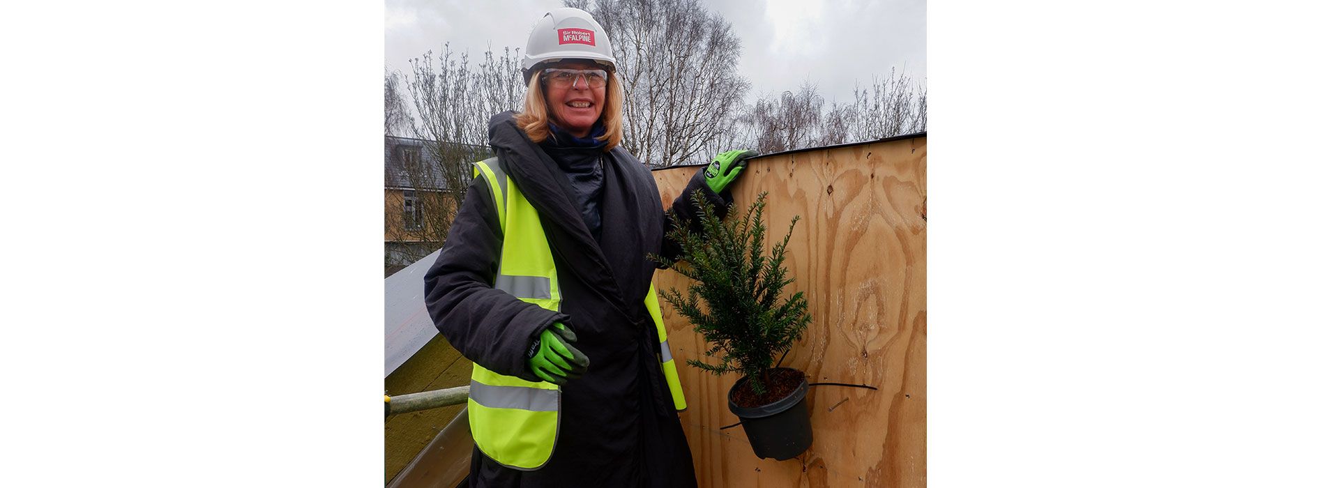 Dame Laura Lee in Northampton posing besides a plant in 'top out' ceremony