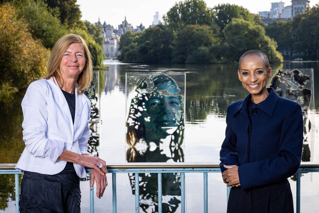 Adele Roberts and Dame Laura Lee smile next to portrait of Laura Lee in London art installation