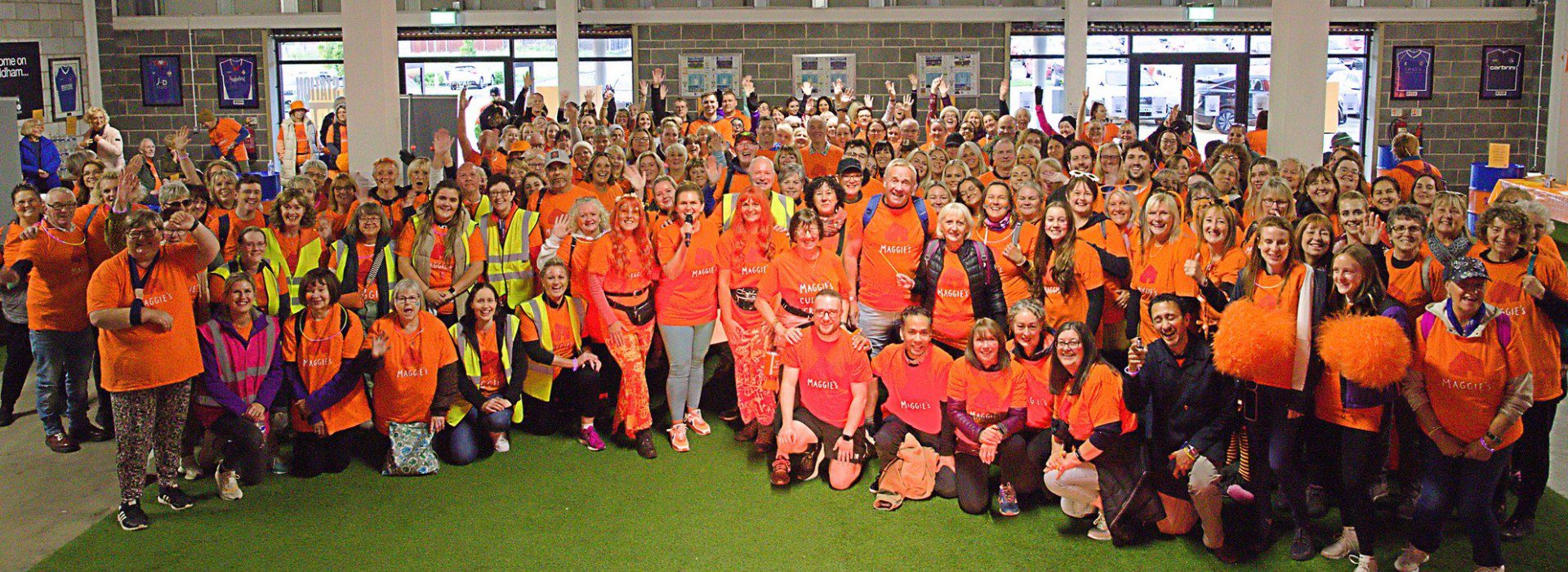 Group of nearly 100 participants, wearing orange Maggie's T-shirts, at a culture crawl fundraising for Maggie's Oldham